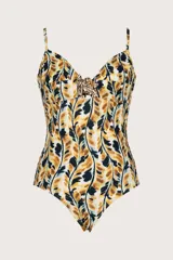 Traje de baño entero con estampado de hojas en tonos mostaza, negro y blanco. Presenta escote corazón con detalle de adorno metálico dorado con forma de hoja en el centro del busto. Tiene tirantes finos ajustables.