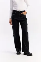 Jean wide leg de tiro medio en color negro, con diseño de corte amplio y detalle de tachas metálicas a lo largo de los laterales y en los bolsillos delanteros.