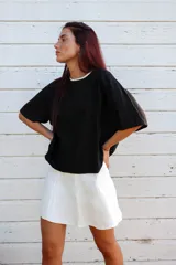 Blusa negra de viscosa texturizada, con cuello a la base con detalle de sesgo a contratono y espalda con escote gota y lazo.