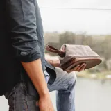 Neceser de lona canvas color verde militar con detalles y base en cuero sintético marrón. Posee apertura superior con cierre metálico y doble bolsillo interno (uno con cierre y otro abierto). La base cuenta con un bolsillo extra con cierre.