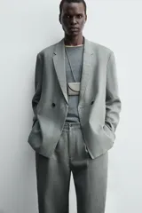 Blazer de corte relajado confeccionada en lino, con diseño de botonadura cruzada, cuello con solapas de muesca, manga larga y bolsillos ocultos en las costuras laterales.