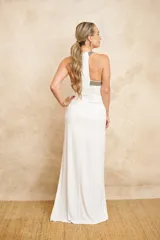 Vestido largo de jersey color blanco, con cuello halter bordado con mostacillas plateadas y tajo lateral en la falda.