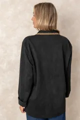 Blazer de gamuza color tostado con diseño artesanal. Presenta flecos en las solapas y bolsillos, bordados florales en los hombros con detalles de perlas colgantes y aplicaciones decorativas en los bolsillos.
