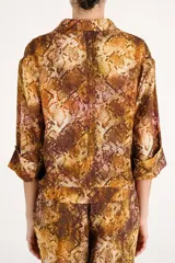 Camisa de viscosa con estampado animal print tipo piel de serpiente en tonos marrones y rojizos, de corte corto, manga larga y cuello clásico.