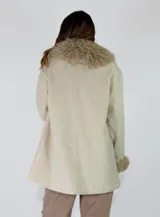 Chaqueta midi color crudo con detalles de piel sintética en el cuello y los puños. Presenta un diseño abierto con bolsillos laterales y una textura suave.