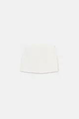 Falda pantalón de tiro bajo en color negro. Presenta falsos bolsillos de vivo en la parte delantera y cierre lateral con cremallera oculta en la costura.