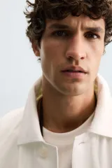 Cazadora de hombre, corte regular fit, color blanco roto, confeccionada en tejido de lino y algodón. Presenta cuello solapa, manga larga con puños abotonados, bolsillos de plastrón en la cadera y cierre frontal de botonadura.