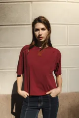 Remera de manga corta color bordó, con cuello redondo y calce boxy. Presenta un pequeño logo bordado en hilo dorado en el pecho.