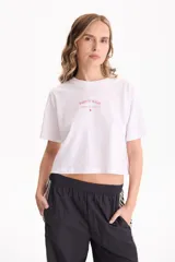 Remera cropped blanca de manga corta y calce cómodo, con estampa frontal en tono rojo con la inscripción "Paris is Magic".