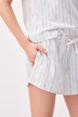 Pijama de algodón compuesto por una remera de manga corta con cuello redondo y un short con cordón ajustable en la cintura, ambos con diseño de rayas verticales formadas por pequeños motivos florales en tonos azules sobre fondo blanco.