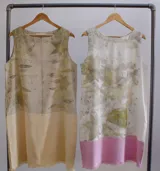 Vestido corto sin mangas, con estampado de hojas en tonos beige y verde, y falda color lila con detalle de flecos en el ruedo.