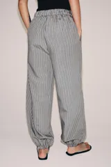 Pantalón de tiro medio con pierna ancha y cintura elástica, confeccionado en mezcla de viscosa con diseño de rayas verticales en tonos mostaza y marrón.