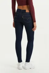 Jean de corte super skinny y tiro medio en color azul oscuro. Presenta costuras en contraste, cierre frontal con botón y cremallera, y diseño de cinco bolsillos.