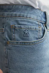 Jean celeste de corte recto con cadera levemente holgada.