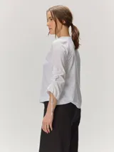 Remera de manga larga color blanco con cuello redondo y detalles fruncidos con lazos en las mangas.