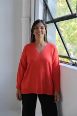 Sweater de punto color naranja, con cuello en V, manga larga y diseño holgado con tajos laterales en el ruedo.
