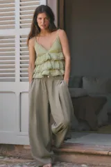 Pantalón fluido de tiro medio color verde militar, con cintura elástica en la parte trasera, pinzas en el delantero y bolsillos laterales ocultos en la costura. Presenta un diseño de pernera ancha y corte tobillero, con cierre frontal de cremallera y botón.