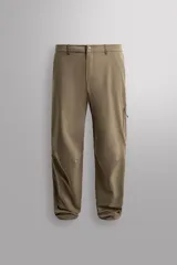 Pantalón técnico de corte regular fit, confeccionado en tejido elástico y compacto. Presenta cintura ajustable con cordón interior, cierre frontal con cremallera y botón, bolsillos laterales y bolsillos con cremalleras ocultas en la pernera y parte trasera. El bajo es ajustable mediante botones a presión.