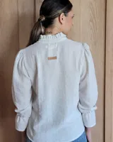 Blusa de algodón color azul, de corte suelto, con mangas largas abullonadas y cuello con volados y escote en V.