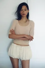 Top de punto fino semitransparente, color beige, con escote redondo y mangas cortas con puños ajustados.
