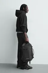 Mochila deportiva de diseño minimalista fabricada en tejido técnico resistente. Cuenta con compartimento principal con cierre de cremallera, bolsillo frontal con cierre, interior con bolsillo organizador, parte posterior acolchada con banda de sujeción para equipaje, asa superior y correas de hombro ajustables.
