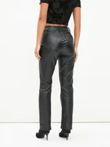 Pantalón recto de cuerina color negro, de tiro alto con bolsillos clásicos y cierre frontal con botón y cremallera.
