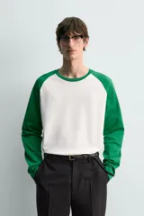 Camiseta de manga larga con diseño raglán, cuerpo color blanco crudo y mangas largas color verde esmeralda.