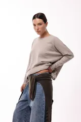 Sweater de silueta amplia y largo medio, con cuello redondo, mangas largas y detalle de botones decorativos en los laterales. Presenta un diseño de tejido de punto con caída relajada.