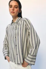 Camisa de corte oversize confeccionada en mezcla de viscosa, con estampado de rayas verticales. Presenta cuello solapa, cierre frontal con botones y mangas largas con puños amplios.