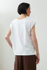 Remera blanca de algodón con mangas cortas y cuello redondo con abertura tipo gota. Presenta un delicado bordado floral en la parte superior delantera.
