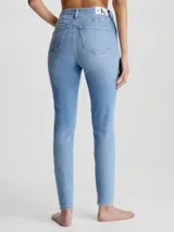 Jean skinny de tiro alto Calvin Klein, color celeste, con bolsillos delanteros y traseros, cierre con cremallera y botón, y etiqueta de cuero con logo en la parte trasera.