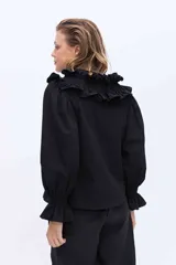 Blusa blanca de algodón con cuello alto fruncido con volados y mangas abullonadas con puños elásticos.