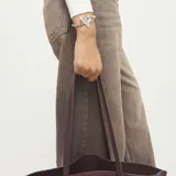 Pulsera semirrígida de aleación de metales bañada en plata de ley, con un dije central en forma de corazón liso y pulido. El cierre es de tipo gancho, y la banda presenta un detalle texturizado de espiral en la parte superior.