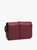 Cartera de hombro de cuero sintético color borgoña, con solapa frontal y cierre metálico con monograma TH. Posee correa ajustable y detalles metálicos dorados.