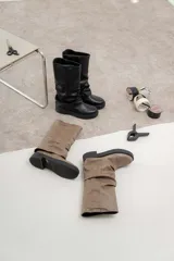 Bota de caña media color negro, confeccionada en cuero sintético con efecto arrugado, suela track y plataforma baja.