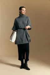 Poncho de tejido de punto color gris, con cuello alto y mangas amplias de diseño holgado.