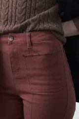 Pantalón de fit recto color beige, confeccionado en cotton spandex. Presenta costuras visibles y bordados decorativos en tono dorado/marrón claro. El ruedo del pantalón tiene un borde festoneado.