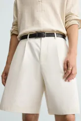 Bermuda de corte regular fit, color blanco hueso, confeccionada en tejido de algodón y lino. Presenta pliegues frontales, bolsillos delanteros y bolsillos traseros de plastrón.
