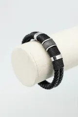 Pulsera de cuero trenzado color negro con detalles metálicos plateados.