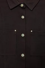 Camisa entallada color marrón oscuro, con cuello camisero y manga larga. Presenta dos bolsillos de plastrón en el delantero y cierre frontal con botones a presión dorados.