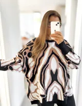 Sweater de punto con diseño oversize y estampado abstracto en tonos negro, beige y blanco. Presenta cuello redondo, mangas largas con puños ajustados y un corte holgado.