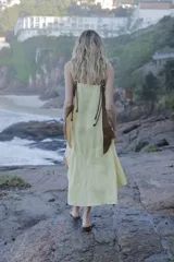 Vestido midi de lino color salmón, de corte amplio y silueta holgada. Presenta diseño con cortes irregulares y detalles de pasamanería en el escote y costuras. Cuenta con breteles dobles tipo cuerda y ruedo asimétrico.