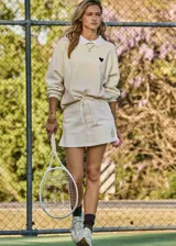 Short pollera blanco de algodón orgánico tejido con cintura con cordón y logo TU bordado en dorado en la parte delantera.