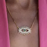 Collar dorado con cadena fina y dije de ojo con piedra color esmeralda.