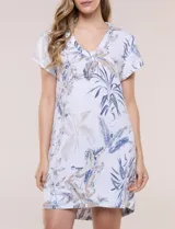 Vestido corto marca Dash confeccionado en mezcla de lino y rayón, color blanco con estampado botánico en tonos azules y beige. Presenta escote en V con cuello tipo camisa, mangas cortas, bolsillos laterales invisibles y una silueta holgada de caída ligera.