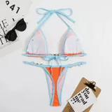 Bikini de dos piezas con corpiño triangular y bombacha colaless. El diseño destaca por sus detalles de cadenas doradas con perlas incrustadas en los breteles del corpiño y en los laterales de la bombacha. Presenta una combinación de colores vibrantes en amarillo y naranja.