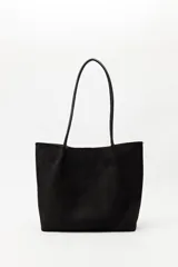 Cartera tipo tote de diseño minimalista y formato amplio, confeccionada en gamuza negra con asas largas y estructura rígida.