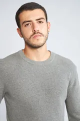 Sweater de punto color mostaza, con cuello redondo y mangas largas.