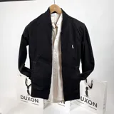Campera bomber negra de gabardina con cierre frontal, cuello, puños y ruedo acanalados. Tiene bolsillos laterales y logo bordado en el pecho.