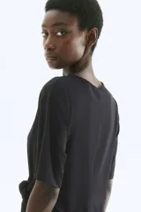 Vestido corto negro de punto con cuello redondo, mangas cortas y detalle de nudo en un lateral.